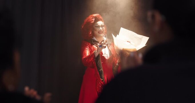 Applause, champagne and flowers with drag performer in theater for lgbt culture, nightlife and spotlight show. Identity, entertainment and winner with person at event for celebration and pride