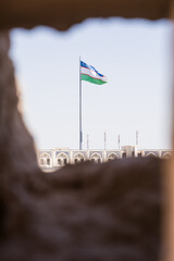 Uzbek flag waving in the wind, seen through a hole in the ancient city wall of Khiva, Uzbekistan