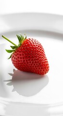 Single, ripe strawberry on a white plate.