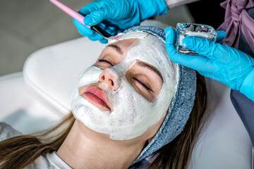 Doctor applying facial mask at cosmetology cabinet on woman face. Close up portrait