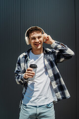 Young caucasian man drinking coffee in front of black wall