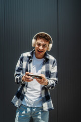 Young caucasian man using smart phone in front of black wall