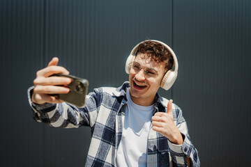 Young caucasian man taking self portrait with smart phone in front of black wall