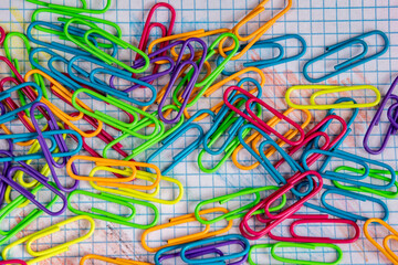 Clips fluorescentes de colores sobre una hoja de cuadros azules