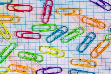Clips fluorescentes de colores sobre una hoja de cuadros azules