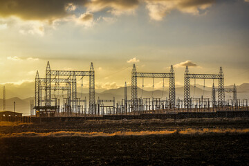 Power line transmission towers in desert at sunset