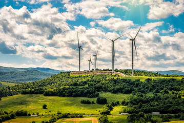 Wind turbines and green mountain nature landscape under sunlight. Green energy concept