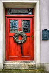Wooden old red door with Christmas wreath in downtown