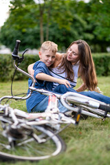 Fototapeta premium Mother and son hugging and playing near bicycle outdoors in park