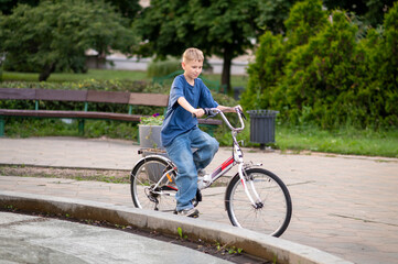 Blond teenage boy riding bicycle in urban park on a sunny day