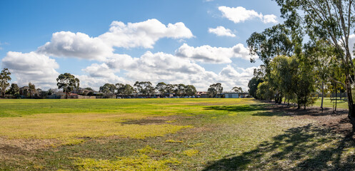 Expansive public reserve in suburban Melbourne Australia, featuring a grass field bordered by...
