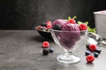 Delicious sorbet with fresh berries and mint in dessert bowl on grey textured table against dark background, closeup. Space for text