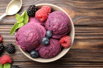Delicious sorbet with fresh berries and mint in bowl on wooden table, flat lay