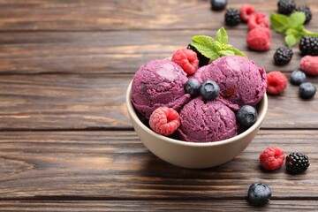 Delicious sorbet with fresh berries and mint in bowl on wooden table, closeup. Space for text