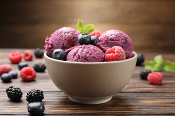 Delicious sorbet with fresh berries and mint in bowl on wooden table against brown background, closeup