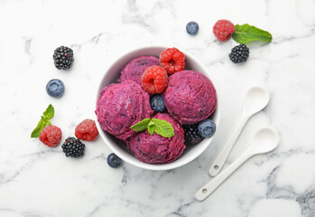Delicious sorbet with fresh berries and mint in bowl on white marble table, flat lay