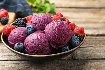 Delicious sorbet with fresh berries in bowl on wooden table, closeup