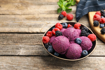 Delicious sorbet and fresh berries in bowl on wooden table, closeup. Space for text