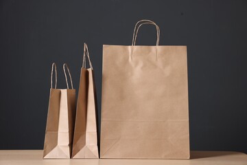 Kraft paper bags on wooden table against dark background, closeup