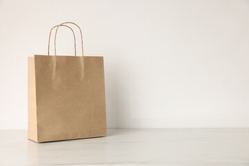 Kraft paper bag on light marble table indoors. Space for text