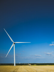 wind turbine on golden harvested field under deep blue sky

