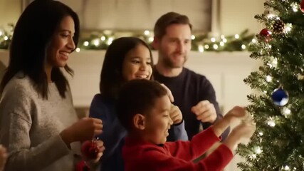 Family joyfully decorating a Christmas tree together in a cozy living room with festive lights
