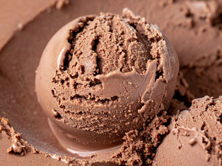 A close-up of a scoop of chocolate ice cream. The ice cream is sitting in a container of ice cream of the same flavor.