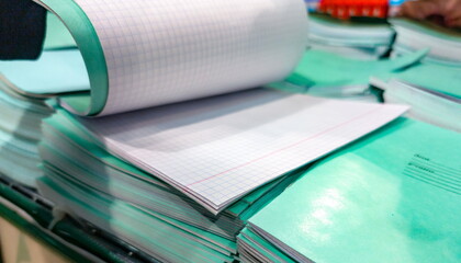 Stacked graph paper pads on a desk in a busy classroom ready for students to use during a creative...