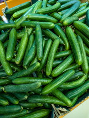 Fresh green cucumbers stacked in a market display inviting shoppers on a sunny day for local produce selection
