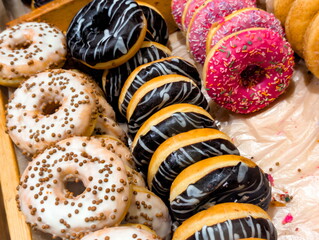 Colorful assortment of donuts displayed on a wooden tray in a bakery inviting customers to indulge...