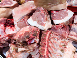 Cuts of fresh pork displayed at a local market during midday, showcasing various sections and textures of the meat