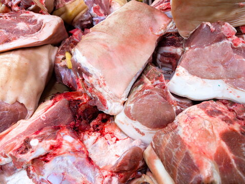 Fresh cuts of pork displayed at a local market showing various parts and textures in vibrant colors during the morning hours