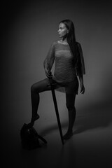Black and white portrait of female knight in chainmail holding sword in the shadows full length