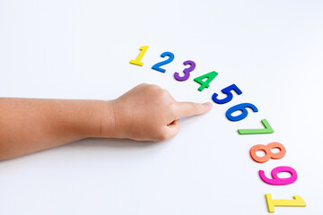 Child hand pointing at sequence of colorful numbers on white background