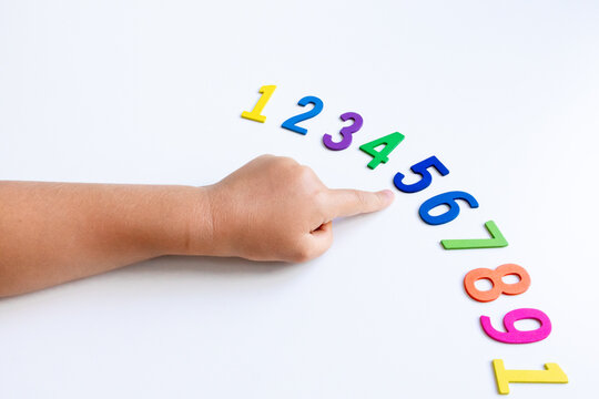 Child hand pointing at sequence of colorful numbers on white background