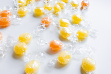 Assorted orange and yellow wrapped hard candies on white background