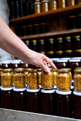 Female hand picking jar of bee pollen in farmer market display
