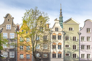 Gdansk, a city on the Baltic coast of northern Poland, Europe. Colorful buildings stand tall, showcasing unique architecture and a glimpse of a church spire in the distance under a bright, sunny sky.