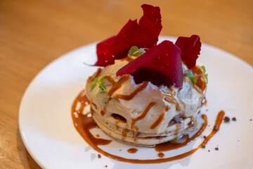 Fluffy pancake stack with cream, and salted caramel sauce, and topped red raspberry tuile
