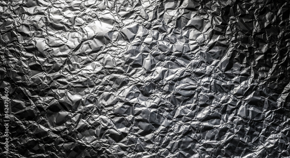 Poster crumpled metallic foil texture, showcasing irregular folds and shadows, creating abstract visual int
