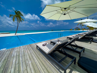 Bedchair near poolside in the tropical blue background