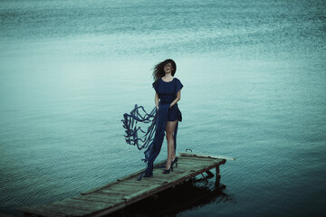 An Elegant Woman Dressed in Blue Graces the Serene Waterside, Capturing Beauty and Charm