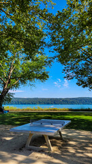 Obraz premium Stationary table to play ping-pong for free in the park of Uberlingen in Germany. There is a lake and a motor boat in the background.