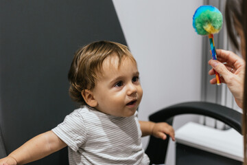 Optometrist examining eyesight of baby boy with colorful toy