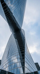 Fototapeta premium Low-angle view of a modern glass skyscraper, reflecting the sky, showcasing architectural design and modernity, symbolizing progress and ambition