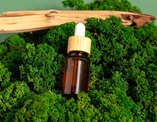 Essential oil bottle surrounded by soft moss on neutral backdrop