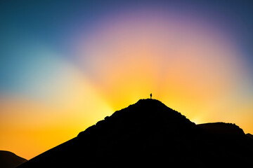 Mountain silhouette against glowing gradient sky, early sunrise, symbolism of elevation, purpose and new beginning