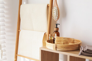 Clean waffle towels and spa products on shelving unit near white wall in bathroom