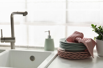 Pink waffle towel on stack of clean plates near sink