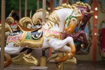 Classic white carousel horse with golden accents and colorful saddle on a fairground ride. Amusement park fun and childhood memory concept.